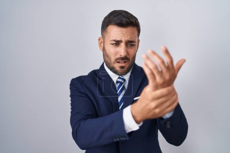 Foto de Hombre hispano guapo vistiendo traje y corbata sufriendo dolor en manos y dedos, inflamación de la artritis - Imagen libre de derechos