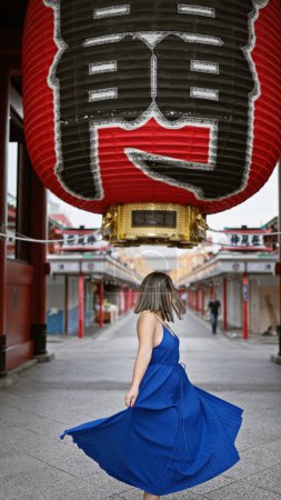 Téléchargez les photos : Une femme hispanique effervescente danse joyeusement, filant dans une belle robe au milieu de la splendide architecture du temple senso-ji à Tokyo. tournée au Japon, elle respire le bonheur dans l'aventure de vacances urbaines. - en image libre de droit
