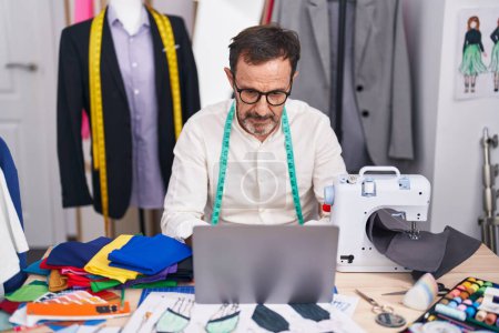 Photo for Middle age man tailor using laptop at tailor shop - Royalty Free Image