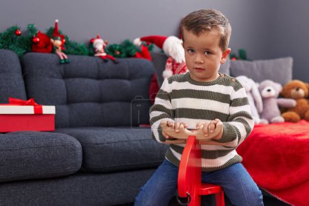 Foto de Adorable chico caucásico jugando con renos meciéndose por la decoración de Navidad en casa - Imagen libre de derechos