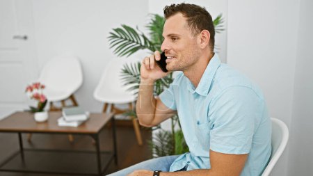 Photo for Handsome man talking on phone in a stylishly furnished room with modern decor. - Royalty Free Image