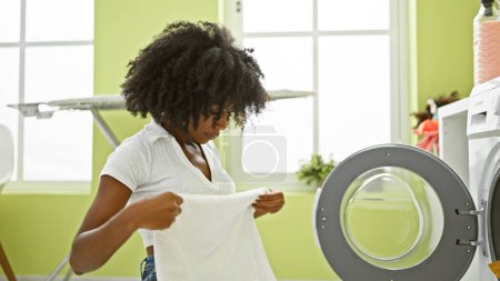 Foto de Mujer afroamericana lavando ropa toalla plegable en la lavandería - Imagen libre de derechos