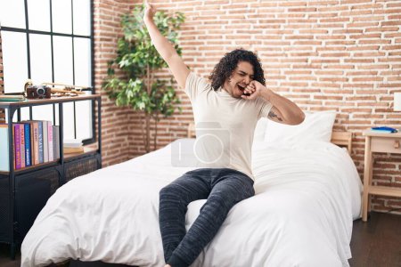 Téléchargez les photos : Young latin man waking up stretching arms yawning at bedroom - en image libre de droit