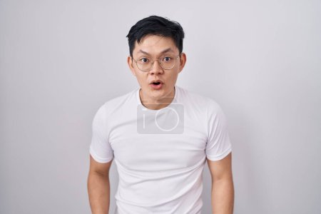 Photo for Young asian man standing over white background afraid and shocked with surprise and amazed expression, fear and excited face. - Royalty Free Image