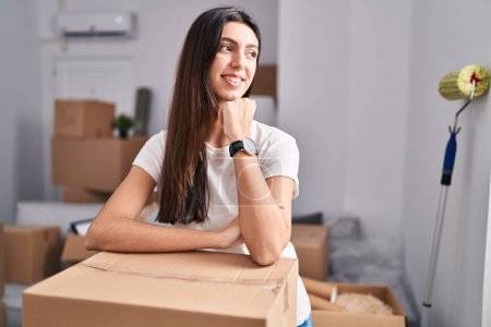 Photo for Young beautiful hispanic woman smiling confident leaning on package at new home - Royalty Free Image