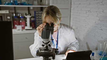 Photo for A caucasian woman scientist meticulously analyzes a sample through a microscope in a well-equipped laboratory indoors. - Royalty Free Image
