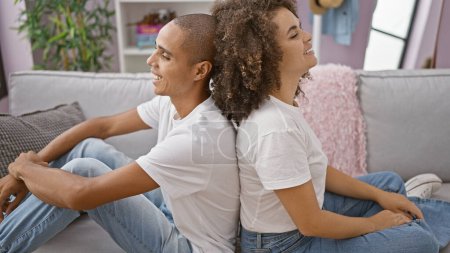 Sonriendo hermosa pareja sentada espalda con espalda en el sofá, disfrutando de la compañía del otro en su acogedora casa