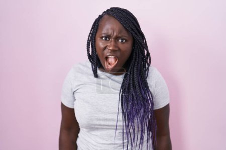 Photo for Young african woman standing over pink background in shock face, looking skeptical and sarcastic, surprised with open mouth - Royalty Free Image