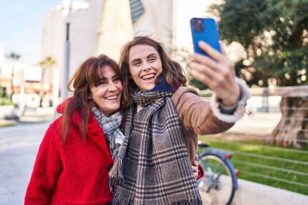 Téléchargez les photos : Two women mother and daughter make selfie by smartphone at park - en image libre de droit