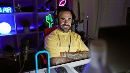 Homme barbu souriant dans une salle de jeux avec des néons la nuit.