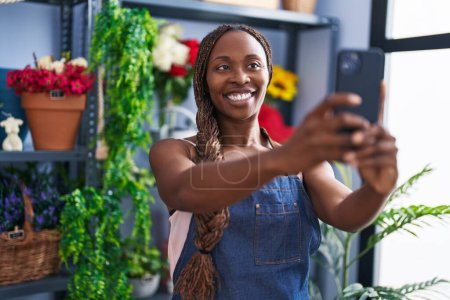 Foto de Florista mujer afroamericana hacer selfie por teléfono inteligente en la tienda de flores - Imagen libre de derechos