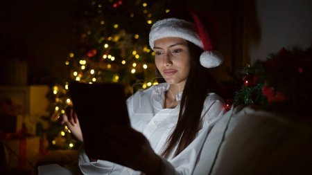 Téléchargez les photos : Jeune belle femme hispanique regarder la vidéo sur touchpad célébrer Noël à la maison - en image libre de droit