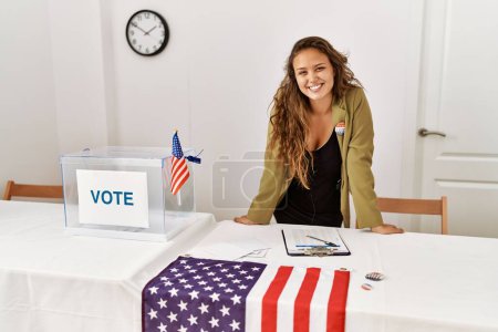 Foto de Young beautiful hispanic woman electoral table president smiling confident at electoral college - Imagen libre de derechos