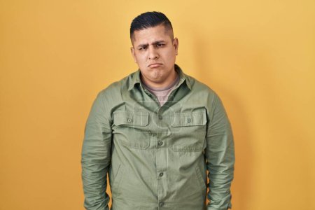 Photo for Hispanic young man standing over yellow background depressed and worry for distress, crying angry and afraid. sad expression. - Royalty Free Image