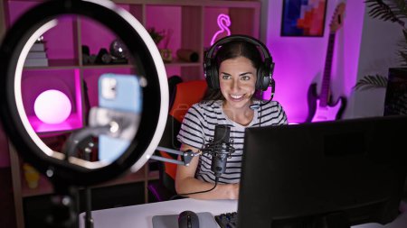 Photo for Gorgeous young hispanic female gamer streaming her epic game night, joyfully playing video games while making interactive video call from her gaming room - Royalty Free Image