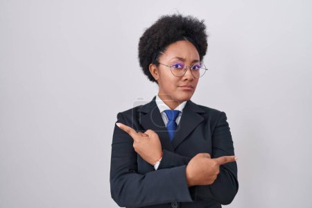Photo for Beautiful african woman with curly hair wearing business jacket and glasses pointing to both sides with fingers, different direction disagree - Royalty Free Image