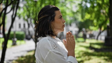 Foto de Hermosa joven hispana rezando y llorando junto a una lápida en el cementerio - Imagen libre de derechos