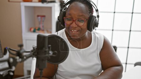 Téléchargez les photos : Une journaliste afro-américaine portant un casque présentant des nouvelles au studio de radio - en image libre de droit