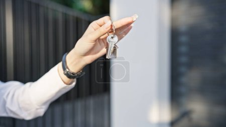 Téléchargez les photos : Gros plan de la main d'une femme tenant les clés d'une maison dans une rue ensoleillée. - en image libre de droit