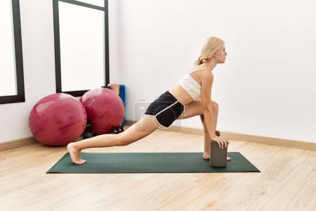 Photo for Young blonde woman training yoga exercise at sport center - Royalty Free Image