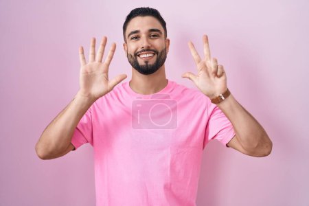 Téléchargez les photos : Jeune homme hispanique debout sur fond rose montrant et pointant vers le haut avec les doigts numéro huit tout en souriant confiant et heureux. - en image libre de droit