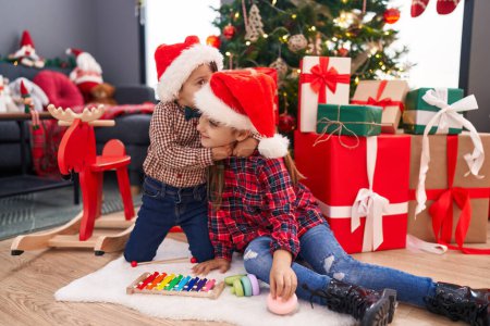 Téléchargez les photos : Adorable garçon et fille s'embrassant et s'embrassant pour célébrer Noël à la maison - en image libre de droit