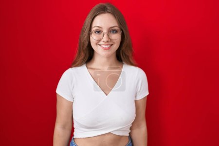 Photo for Young caucasian woman standing over red background with a happy and cool smile on face. lucky person. - Royalty Free Image