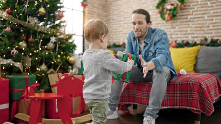 Téléchargez les photos : Père et fils tenant cadeau de Noël à la maison - en image libre de droit
