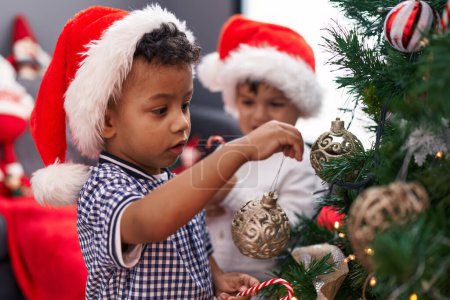 Foto de Adorables chicos decorando el árbol de navidad en casa - Imagen libre de derechos