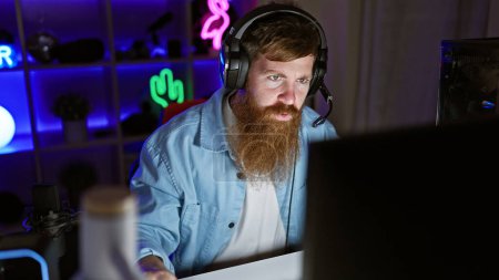 Photo for Handsome irish redhead streamer locked in serious game on his decked-out gaming rig, night streaming session from his decked-out gaming room - Royalty Free Image