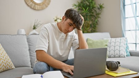 Photo for Stressed out young hispanic teenager sitting, studying on his laptop at home, face focused, struggling with online education on the living room sofa - Royalty Free Image