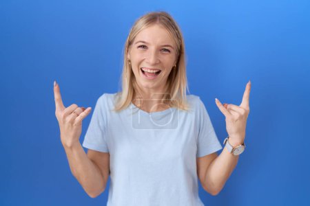 Photo for Young caucasian woman wearing casual blue t shirt shouting with crazy expression doing rock symbol with hands up. music star. heavy music concept. - Royalty Free Image