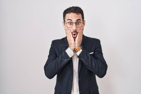 Photo for Handsome business hispanic man standing over white background afraid and shocked, surprise and amazed expression with hands on face - Royalty Free Image