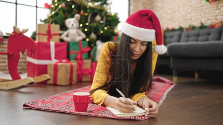Téléchargez les photos : Jeune belle femme hispanique célébrant Noël écriture sur ordinateur portable à la maison - en image libre de droit