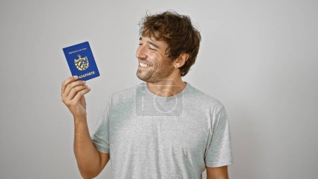 Téléchargez les photos : Jeune homme tenant passeport de cuba souriant sur fond blanc isolé - en image libre de droit