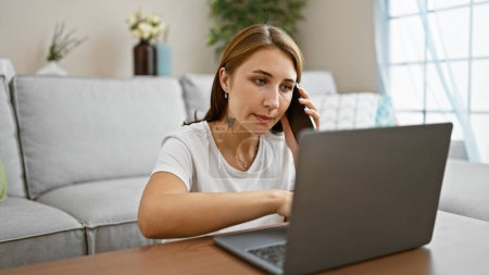 Téléchargez les photos : Jeune femme parlant sur smartphone en utilisant un ordinateur portable assis sur le sol à la maison - en image libre de droit