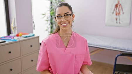 Photo for Confident and smiling young hispanic woman, a beautiful therapist enjoying her work in physiotherapy with a happy expression at a rehab clinic - Royalty Free Image