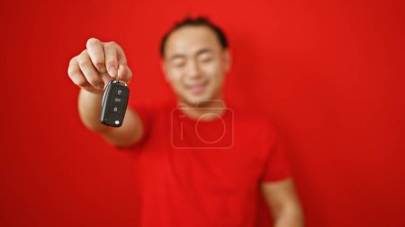 Photo for Joybursting, handsome young asian man confidently smiling, standing over red background, enjoys holding new car key - Royalty Free Image