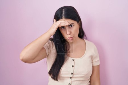 Téléchargez les photos : Young hispanic woman standing over pink background worried and stressed about a problem with hand on forehead, nervous and anxious for crisis - en image libre de droit