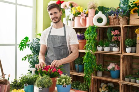 Téléchargez les photos : Jeune homme caucasien fleuriste plantes coupantes à la boutique de fleurs - en image libre de droit