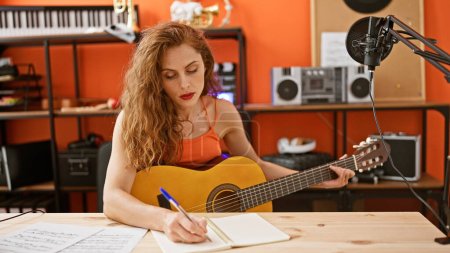 Photo for Caucasian woman songwriting with guitar in a music studio - Royalty Free Image