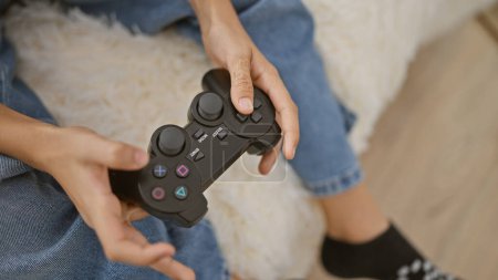 Photo for Adorable caucasian child caught in comfort of home; kid's hands masterfully control gamepad while playing video game sitting on living room sofa, immersed in an indoor world of online gaming ambiance - Royalty Free Image