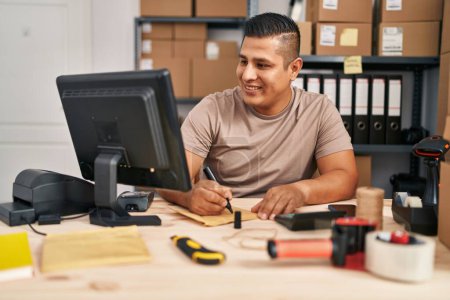 Photo for Young latin man ecommerce business worker writing on package at office - Royalty Free Image