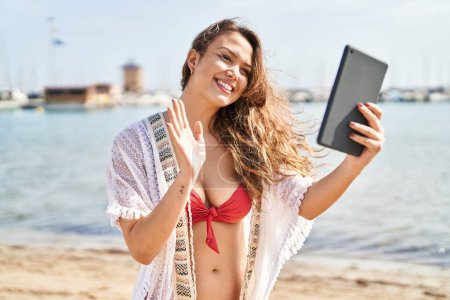 Téléchargez les photos : Young beautiful hispanic woman tourist wearing bikini having video call at beach - en image libre de droit