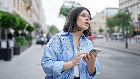 Foto de Joven mujer hispana hermosa usando smartphone esperando un taxi en las calles de Viena - Imagen libre de derechos