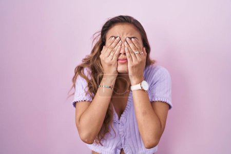 Foto de Young hispanic woman standing over pink background rubbing eyes for fatigue and headache, sleepy and tired expression. vision problem - Imagen libre de derechos