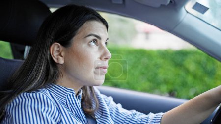 Foto de Joven mujer hispana hermosa conduciendo un coche en la carretera - Imagen libre de derechos