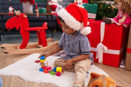 Photo for African american boy playing with toy sitting on floor by christmas tree at home - Royalty Free Image