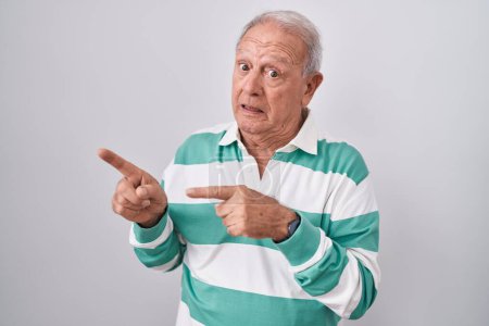 Photo for Senior man with grey hair standing over white background pointing aside worried and nervous with both hands, concerned and surprised expression - Royalty Free Image