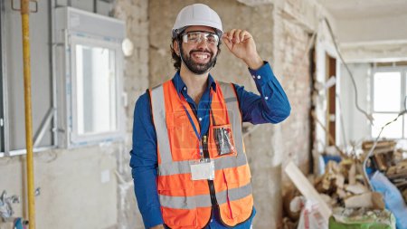 Téléchargez les photos : Jeune homme hispanique architecte souriant confiance debout sur le chantier de construction - en image libre de droit
